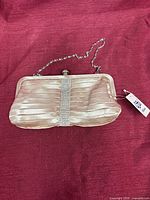 Exterior view of HiJean champagne satin clutch with chain strap and attached tag