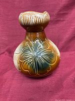 Front view of brown ceramic vase with raised floral motif