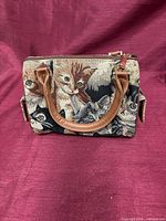 Front view of cat motif tapestry barrel handbag with brown handles