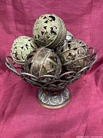 Group of seven mixed-metal filigree spheres displayed in a metal pedestal basket