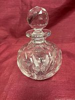 Front view of round crystal decanter with stopper showing floral etching