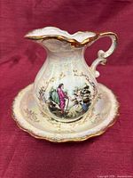 Pitcher resting in basin showing iridescent glaze, gilt trim and transfer scene