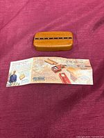 top view of wooden secret puzzle box beside folded brochure