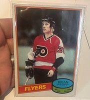 Card in penny sleeve held by hand, showing front image and team/logo details