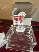 Front view of Campbell’s Kid figurine with box and styrofoam