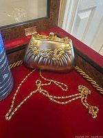 Front view of metallic clutch showing floral embossing and chain