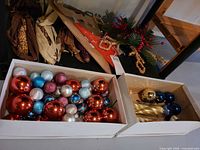 Two boxes of assorted baubles in various colors and swirl designs, plus box with gold ornaments and icicle shapes; wreath and star topper visible