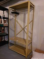 Full view of beige metal shelving rack with garment rod and hangers