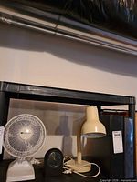 Front view of fan, lamp and clock on shelf