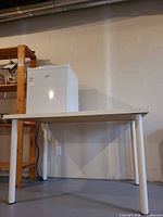 Full view showing rectangular white desk with four round legs