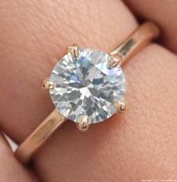 Top view of ring worn on finger showing round brilliant diamond in six-prong setting