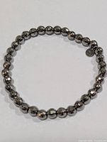 Full view of bracelet showing faceted metallic beads and tag charm