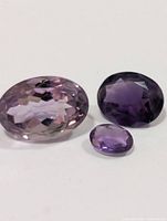 Three faceted amethyst gemstones on plain background