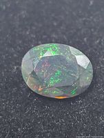 Top view of oval black opal showing green and red flashes