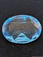 Top view of oval blue topaz showing facets and color