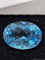 Close-up of oval blue topaz showing facets and color