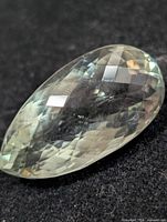 Oblique view of faceted pear-shape green amethyst on dark background