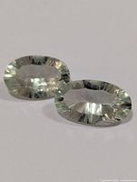 Two oval faceted pale green gemstones front view