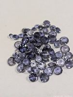 Group of small round faceted iolite stones on neutral background