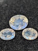 Three faceted oval moonstones on dark background
