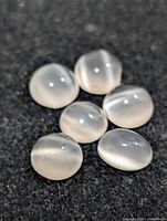 Group of six translucent white cabochon stones on black background