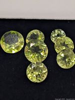 Top view of eight round faceted peridot gems on black background