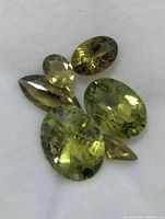 Five loose faceted peridot gemstones grouped together