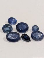 Group of seven faceted blue sapphires on white background