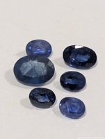 Six loose oval blue sapphires on white background