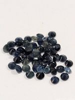 Pile of small round blue sapphires on white background