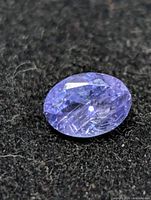 Close view of oval violet-blue tanzanite on dark fabric