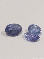 Three loose tanzanite gemstones on white background
