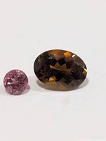 Pink round-cut stone and brown-gold oval-cut stone side by side