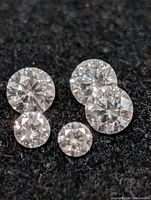 Four loose round brilliant diamonds on black surface