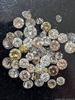 Group of loose fancy colour diamonds on black surface