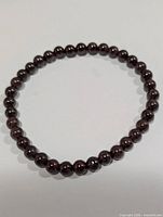 Full view of circular garnet bead bracelet showing overall design and bead color