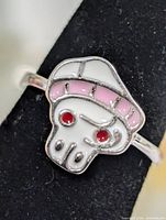 Front view of silver ring showing skull motif with pink hat and red eyes