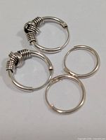 Four silver hoop earrings, two with coil detail, two plain