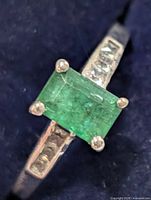 angled view showing emerald-cut center stone and CZ accents