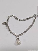 Full view of silver rolo-link bracelet with pearl charm and clasp