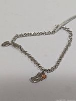 Full view of silver chain bracelet with curved charm and diamond flower accent