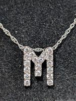 Front view of cubic zirconia letter M pendant on silver chain