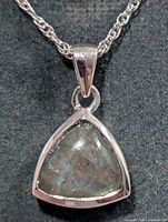 Close-up of triangular labradorite pendant in silver bezel on chain