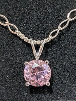 Close-up of pink cubic zirconia pendant in four-prong setting on silver chain