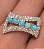 Ring on finger showing overall design and stones