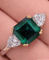 Ring worn on finger showing green centre stone and side CZs