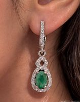 Earring worn in ear to show size, emerald center with CZ halo