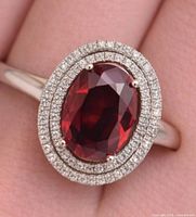 Front view of ring on finger showing garnet and double halo