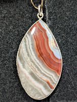 Front view of teardrop crazy lace agate pendant showing banded stone within silver bezel