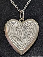 Front view of heart locket on chain showing "LOVE" engraving